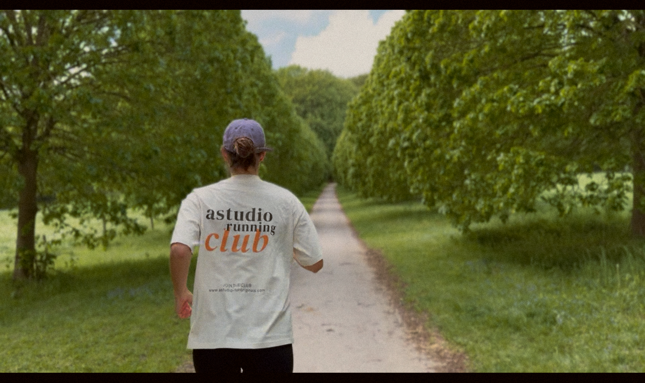 Läuferin im astudio running club Shirt auf einer Baumallee